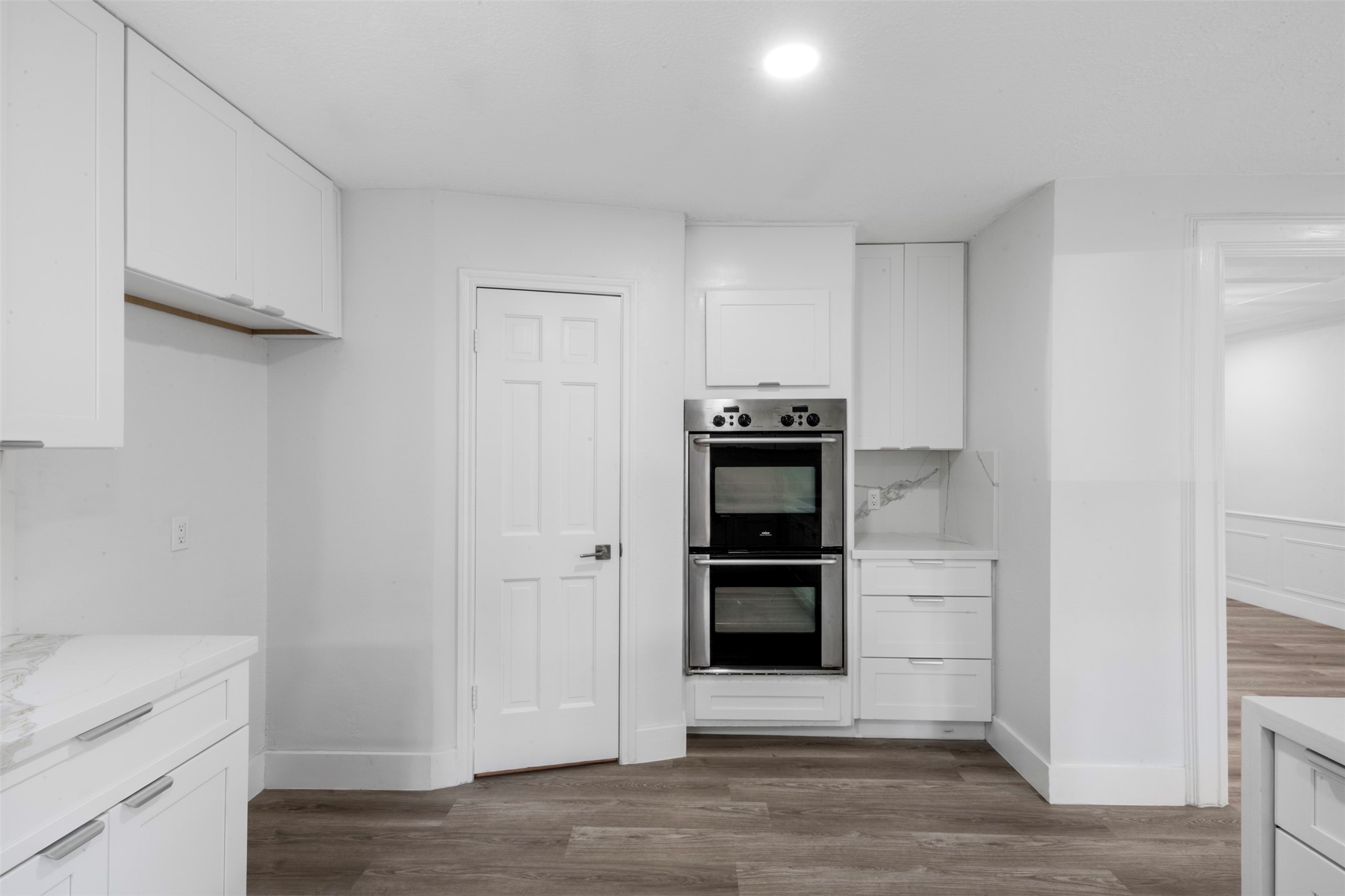 9543 Enstone Circle Spring, TX 77379 - Photo 10 of 50 This kitchen features modern white cabinetry, a built-in double oven, and sleek countertops. The space is bright with recessed lighting and has a contemporary design with light wood flooring.