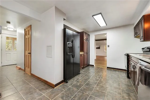 a view of a refrigerator in kitchen and wooden cabinets