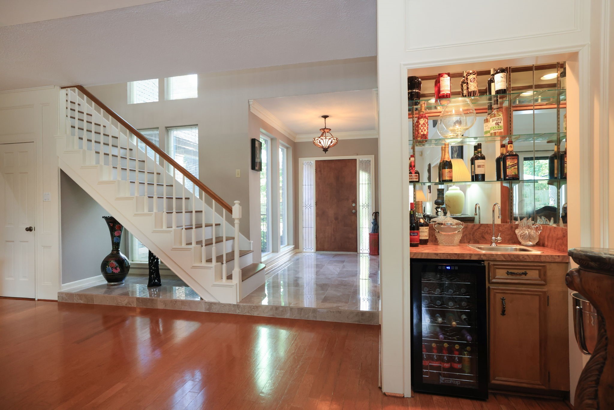 16123 Chasemore Drive Spring, TX 77379 - Photo 14 of 50 This stylish entryway with a staircase feature beautiful tile floors and wall of windows, a small bar area with a wine cooler and mirrored shelves, adds a nice feature for entertaining.