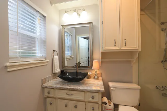 a bathroom with a granite countertop sink a toilet and a mirror