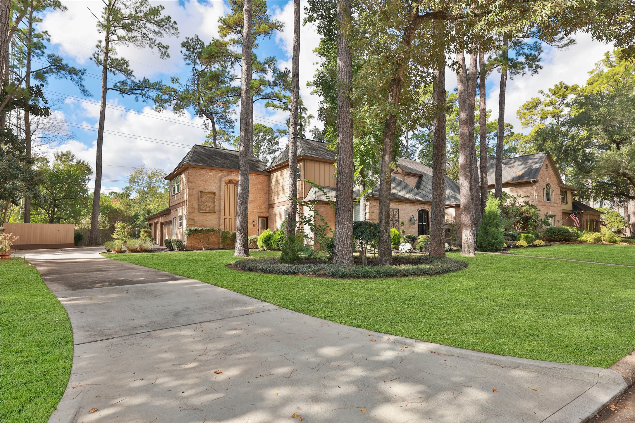16123 Chasemore Drive Spring, TX 77379 - Photo 3 of 50 This photo showcases a spacious, two-story brick home surrounded by tall trees, with a long driveway leading up to an oversized 3-car garage.