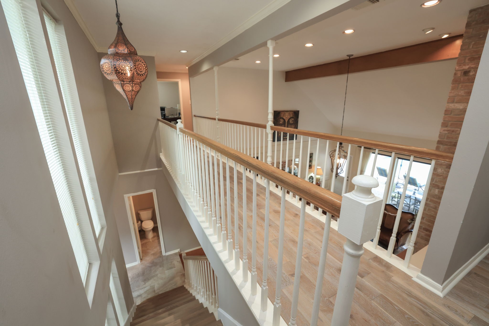 16123 Chasemore Drive Spring, TX 77379 - Photo 31 of 50 This photo showcases a bright, open cat walk with a wooden staircase, elegant pendant lighting, and large windows.