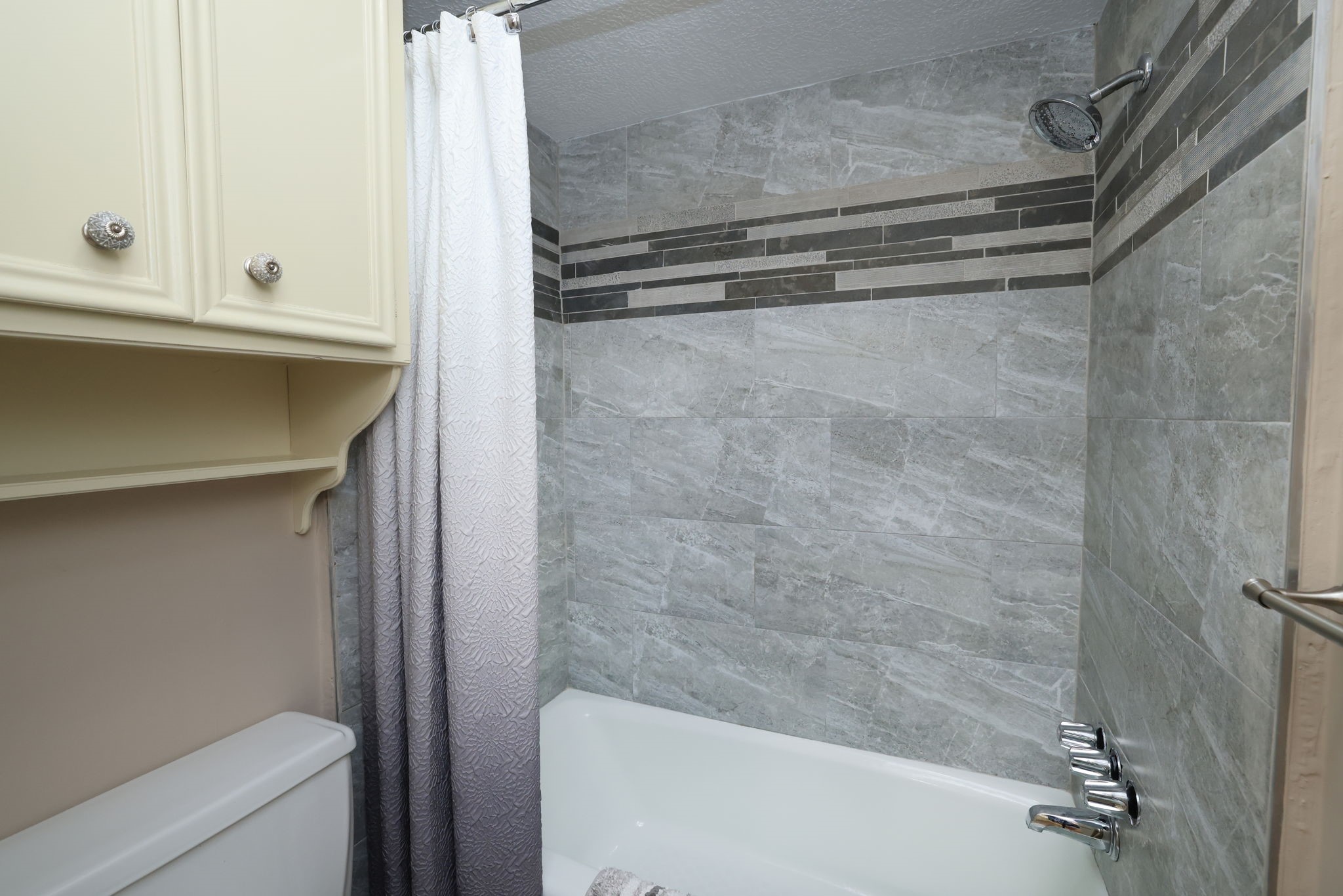 16123 Chasemore Drive Spring, TX 77379 - Photo 35 of 50 This remodeled bathroom features a modern shower with gray tile and decorative accents.