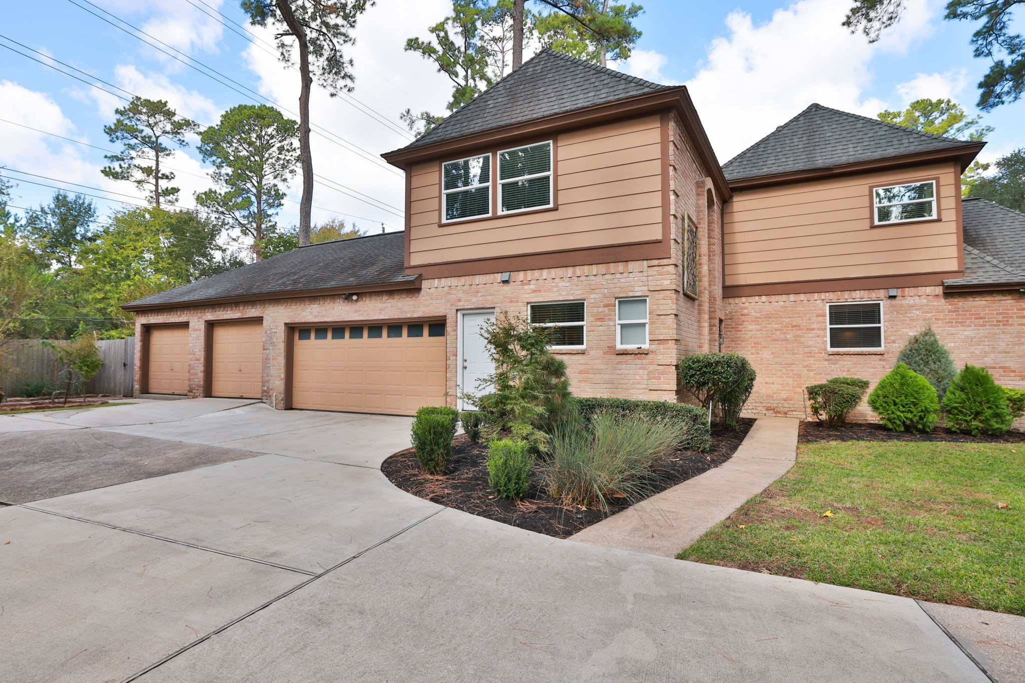 16123 Chasemore Drive Spring, TX 77379 - Photo 42 of 50 This two-story home features a spacious three-car garage, a brick and siding exterior, and a well-maintained front yard with landscaped greenery. The driveway is expansive, offering ample parking space.