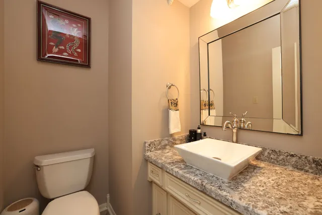 a bathroom with a granite countertop toilet sink and mirror