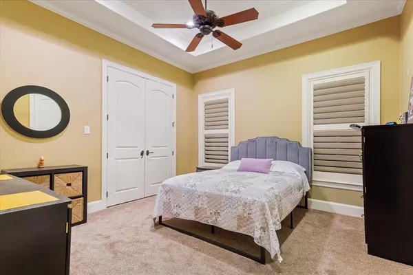 a bedroom with a bed a dresser and a chandelier