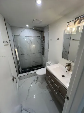 a bathroom with a sink a toilet a mirror and shower