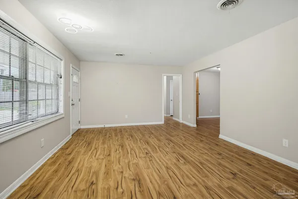 a view of an empty room with wooden floor and a window