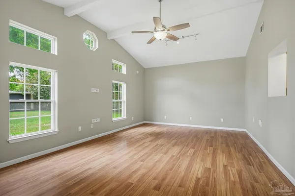 a view of an empty room with a window and wooden floor