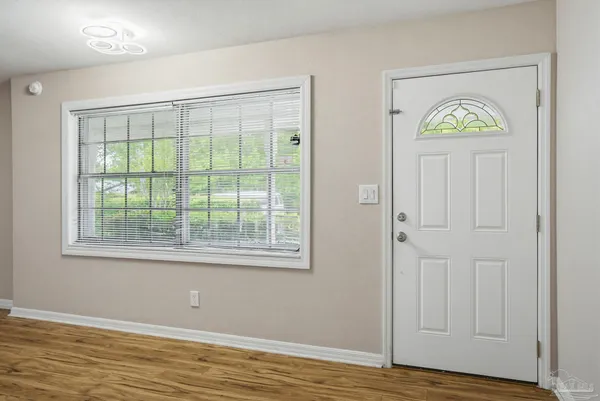a view of an empty room with window and wooden floor
