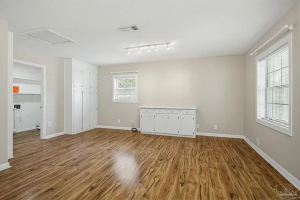 an empty room with wooden floor and windows