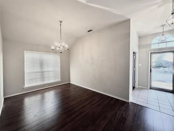 an empty room with wooden floor cabinet and windows