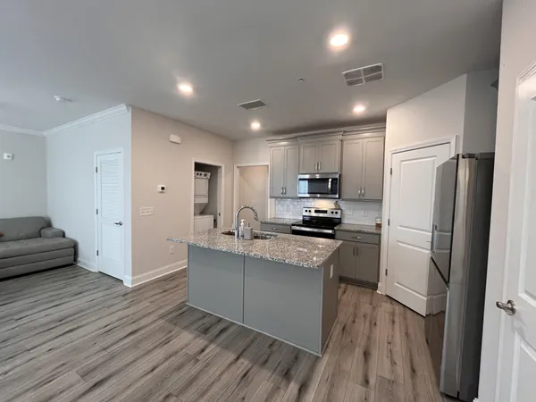 a kitchen with stainless steel appliances granite countertop a refrigerator a sink dishwasher a stove and white countertops with wooden floor