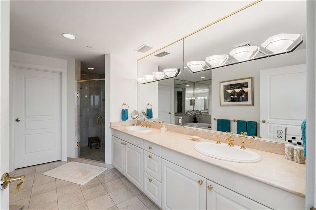 700 Park Regency Place Northeast, Unit 2201 Atlanta, GA 30326 - Photo 23 of 47 a spacious bathroom with a sink a large mirror and a shower