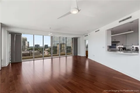 a view of an empty room with wooden floor and a window