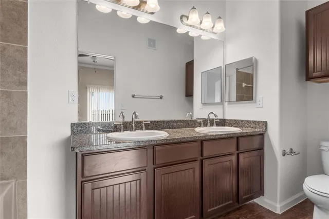 a bathroom with a granite countertop sink a large mirror and a toilet