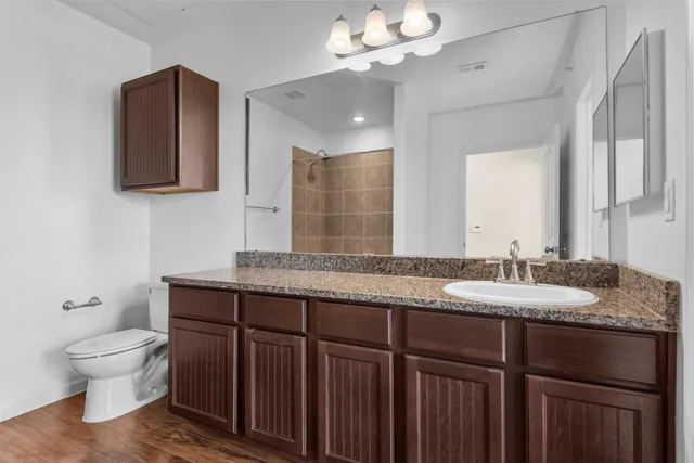 a bathroom with a granite countertop sink a toilet and a mirror