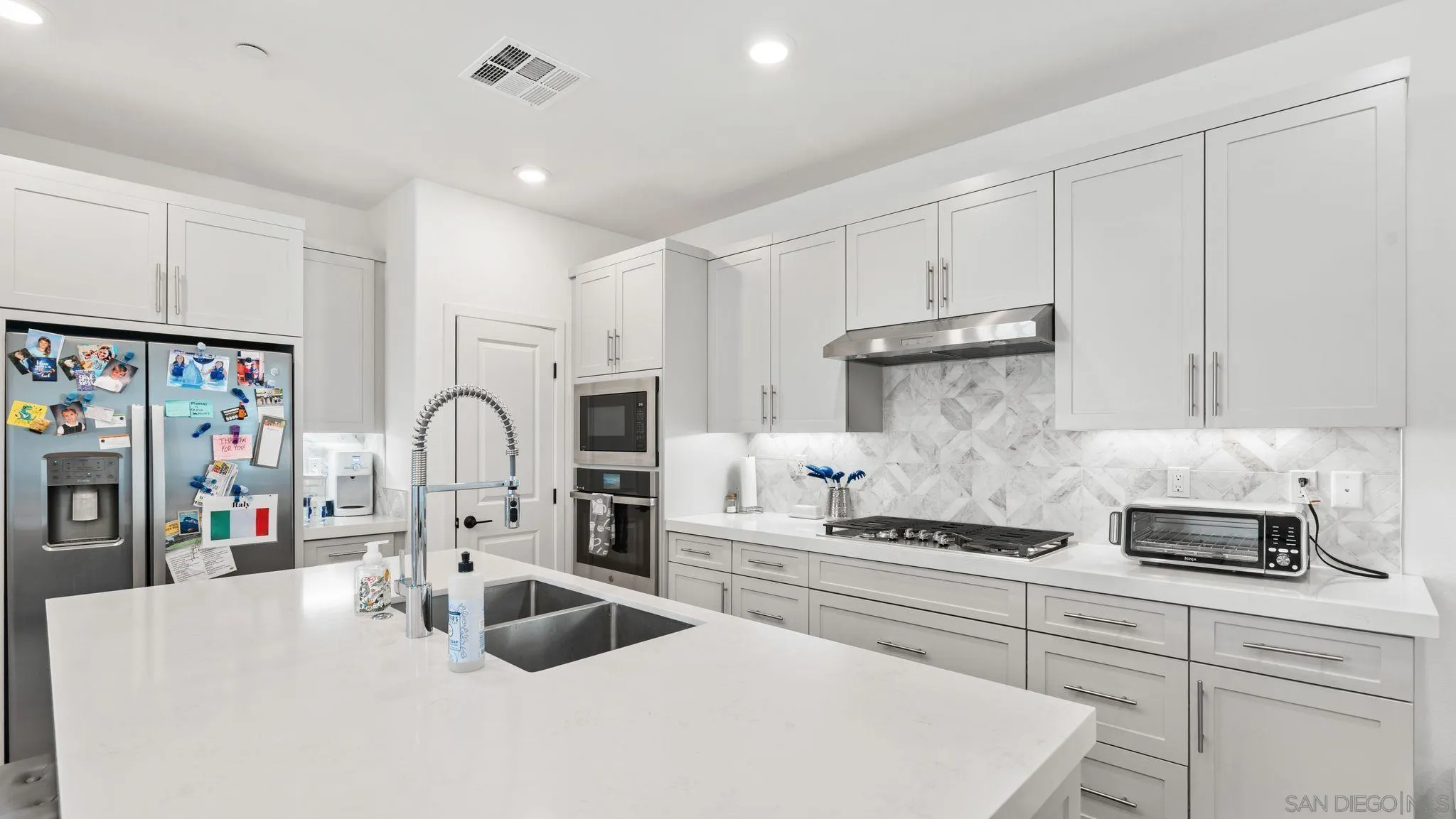15681 Rennyson Way San Diego, CA 92129 - Photo 5 of 36 a kitchen with stainless steel appliances granite countertop a sink refrigerator and cabinets