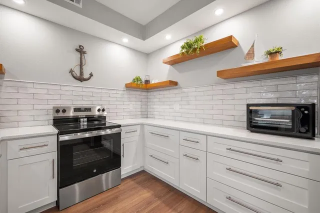 a kitchen with stainless steel appliances white cabinets and a stove top oven