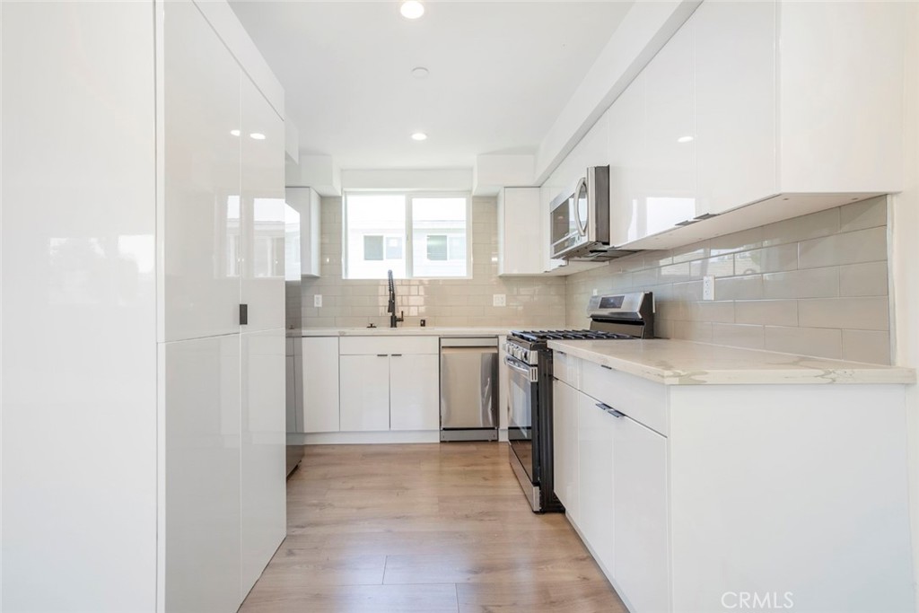 1843 West 20th Street Los Angeles, CA 90007 - Photo 19 of 38 a kitchen with a sink a stove cabinets and a refrigerator