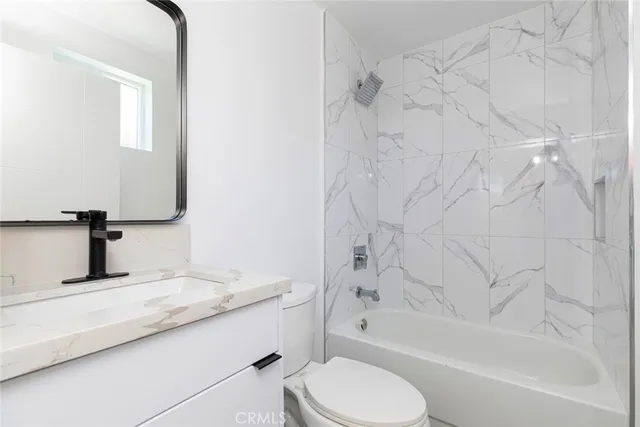 a bathroom with a granite countertop bathtub sink vanity mirror and toilet