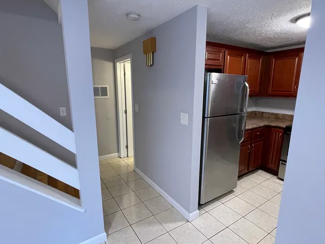 a view of a refrigerator in kitchen and an empty room