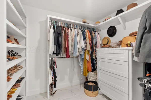 a view of walk in closet with clothes and shoes