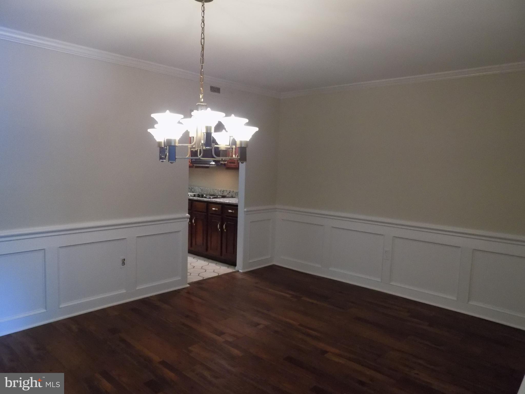 702 Towne Center Drive Joppa, MD 21085 - Photo 16 of 45 a room with a chandelier and wooden floor
