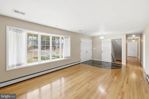 a view of an empty room with wooden floor and a window
