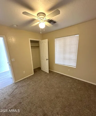 an empty room with a chandelier fan and windows