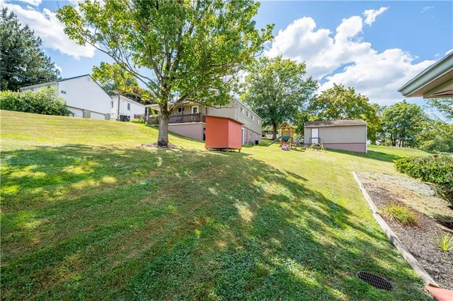 a view of a house with a yard and a large tree