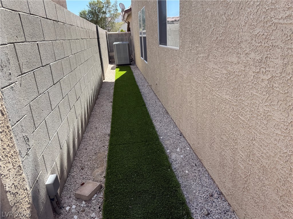 1141 Cathedral Ridge Street Henderson, NV 89052 - Photo 70 of 77 This narrow exterior walkway features artificial turf and gravel for low-maintenance outdoor living.