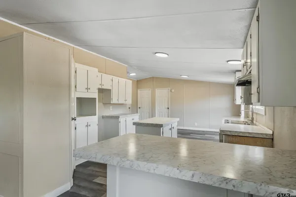 a large kitchen with stainless steel appliances a large counter top and a refrigerator