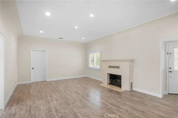 a view of empty room with wooden floor and fireplace