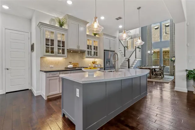 a kitchen with stainless steel appliances granite countertop a sink a stove and a wooden floor