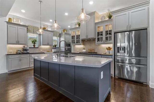 a kitchen with stainless steel appliances granite countertop a refrigerator a sink dishwasher a stove and white cabinets with wooden floor