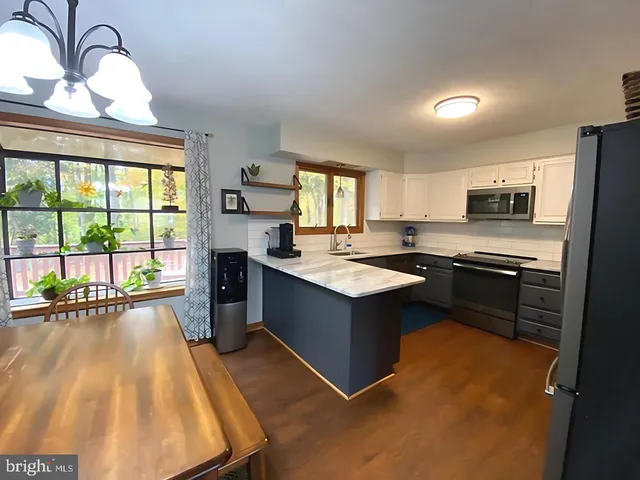 a kitchen with stainless steel appliances granite countertop a stove top oven a sink dishwasher a dining table and chairs with wooden floor