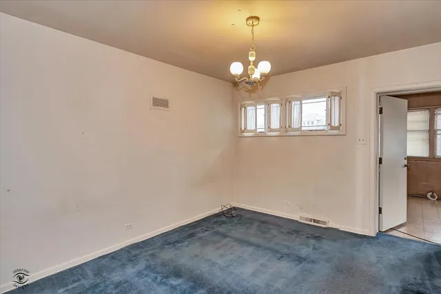 an empty room with a chandelier fan and windows