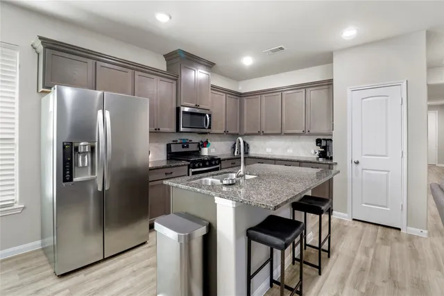 a kitchen with kitchen island a refrigerator stove microwave and cabinets