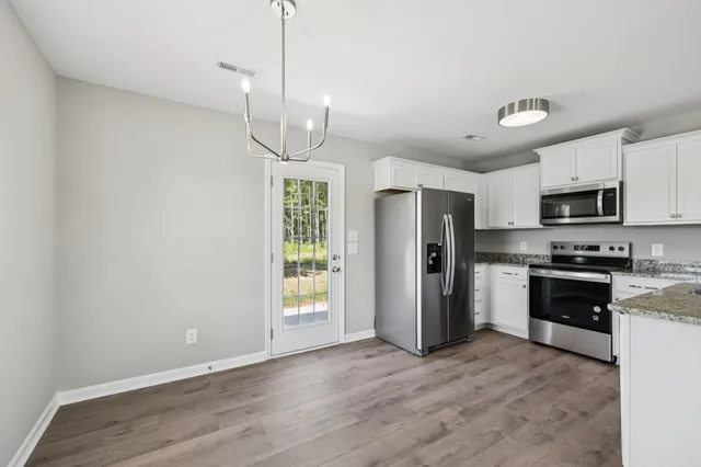 a kitchen with granite countertop a stove a sink and a refrigerator