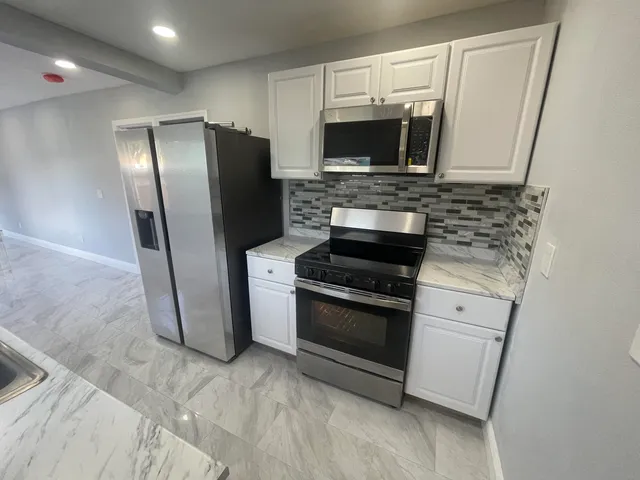 a kitchen with stainless steel appliances granite countertop a refrigerator microwave and sink