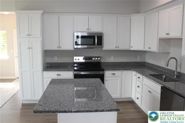 a kitchen with granite countertop white cabinets and stainless steel appliances