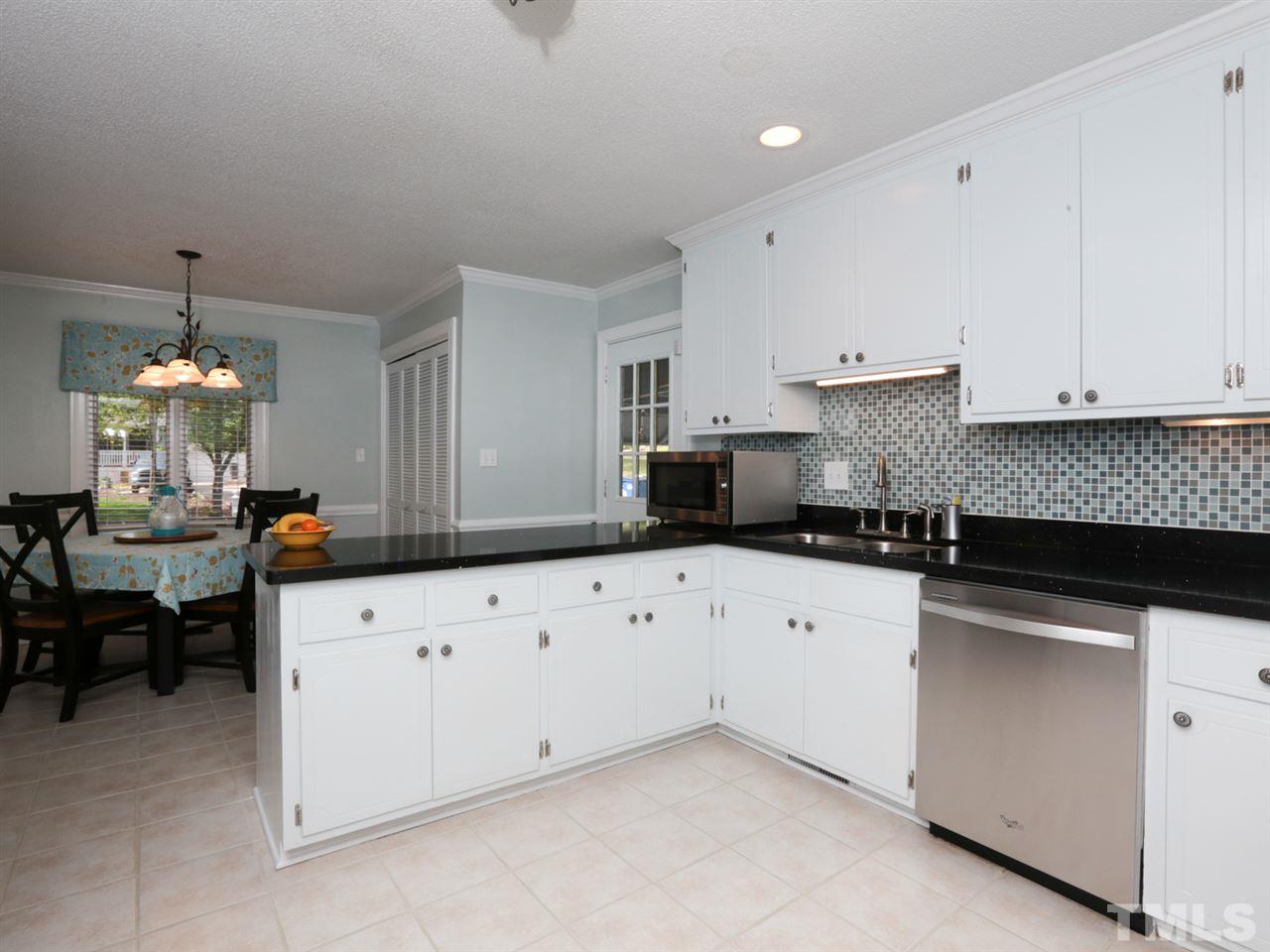 7309 Phellos Court Raleigh, NC 27615 - Photo 11 of 19 a kitchen with granite countertop white cabinets white stainless steel appliances with a sink and dishwasher