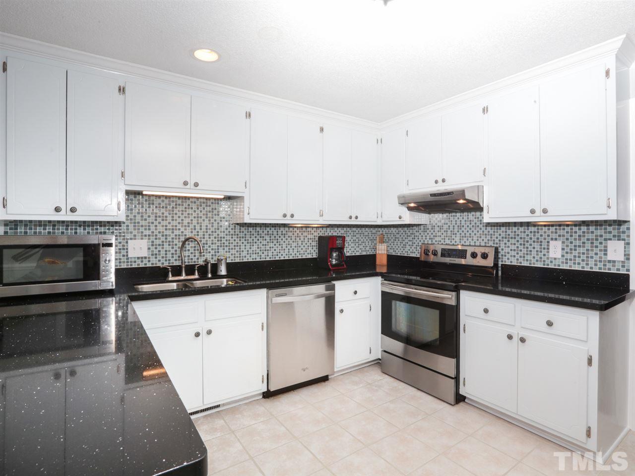 7309 Phellos Court Raleigh, NC 27615 - Photo 6 of 19 a kitchen with granite countertop a sink stainless steel appliances and white cabinets
