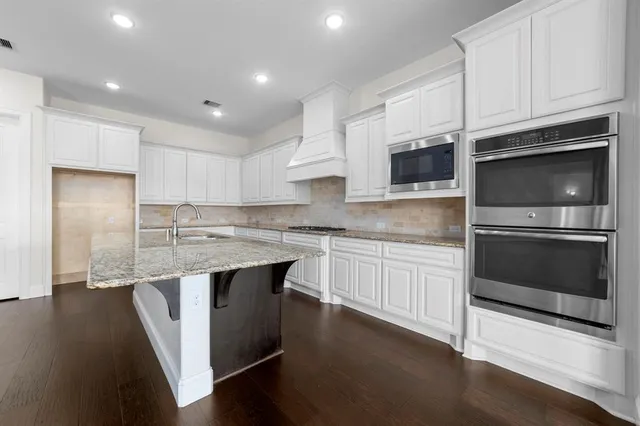 a kitchen with stainless steel appliances kitchen island granite countertop a stove a sink and a microwave