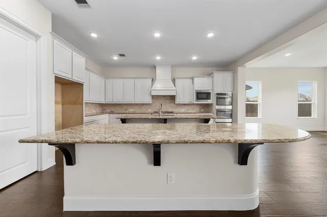 a large kitchen with granite countertop stainless steel appliances sink a microwave and cabinets