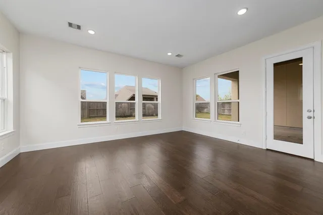 a view of an empty room with wooden floor and windows