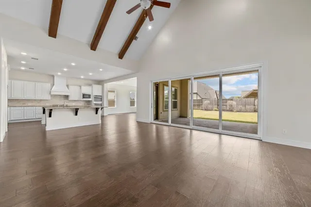 a view of an empty room with wooden floor and a kitchen