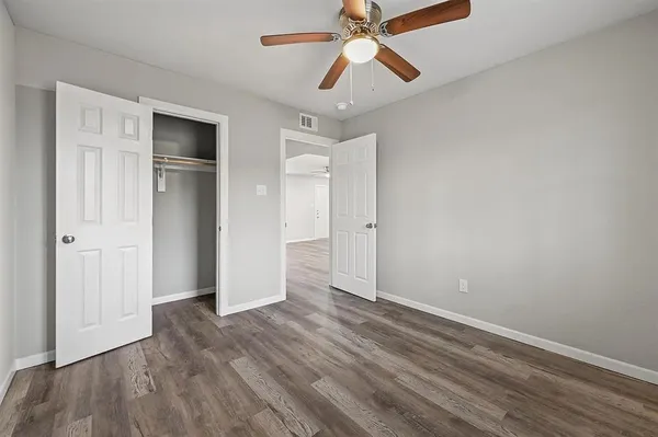 an empty room with wooden floor closet and windows