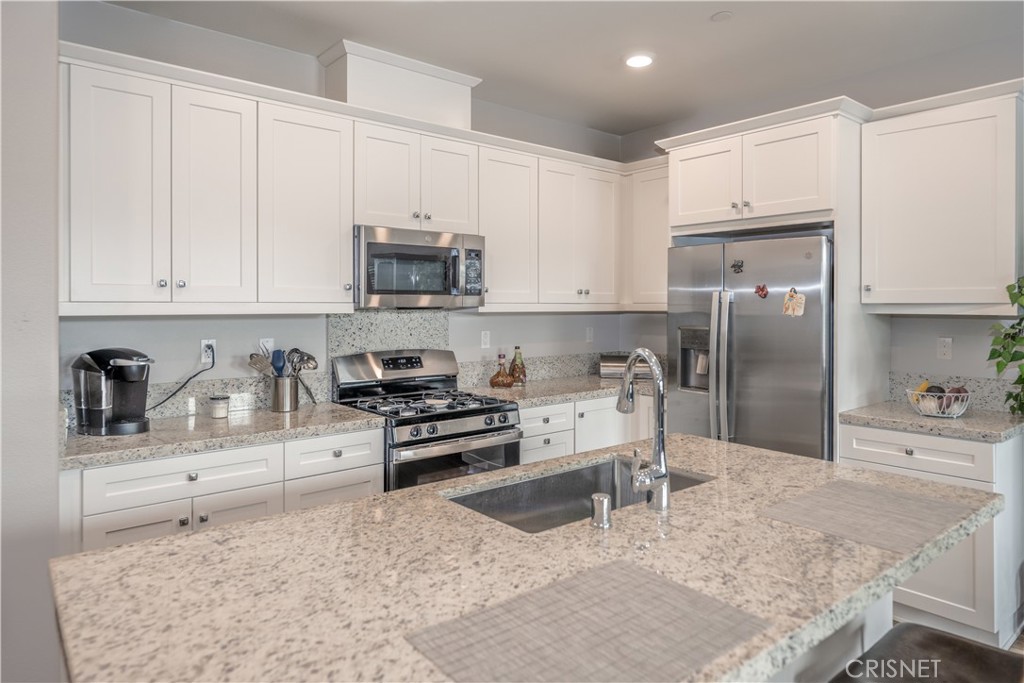 a kitchen with stainless steel appliances granite countertop a stove a sink and a refrigerator